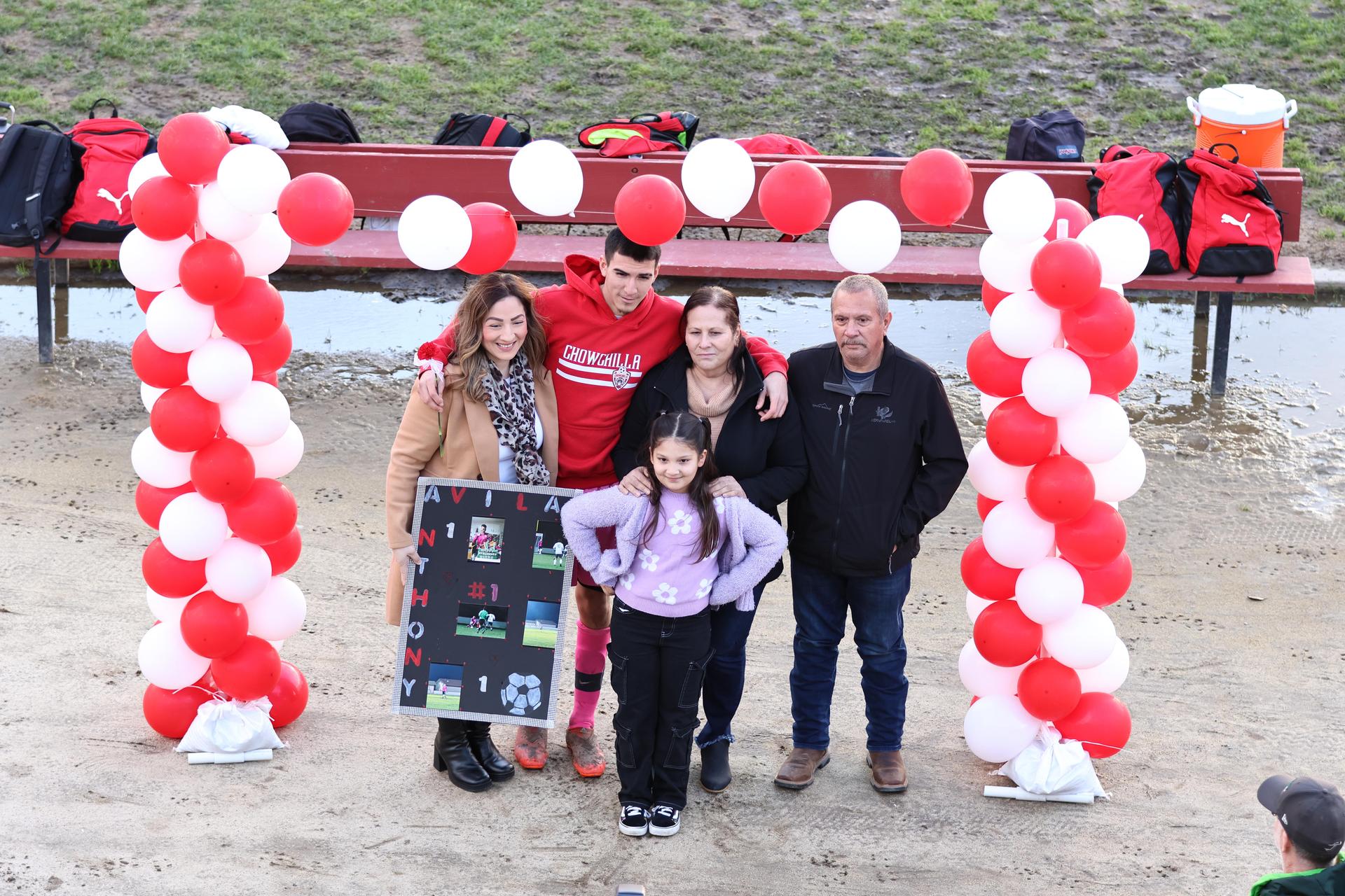 seniors and their escorts posing beneath a balloon arch