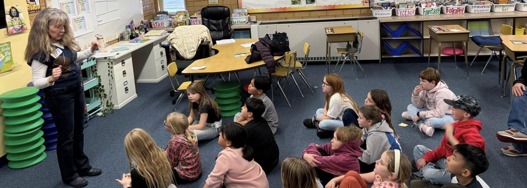 Teacher engaging a group of attentive students in a colorful classroom.
