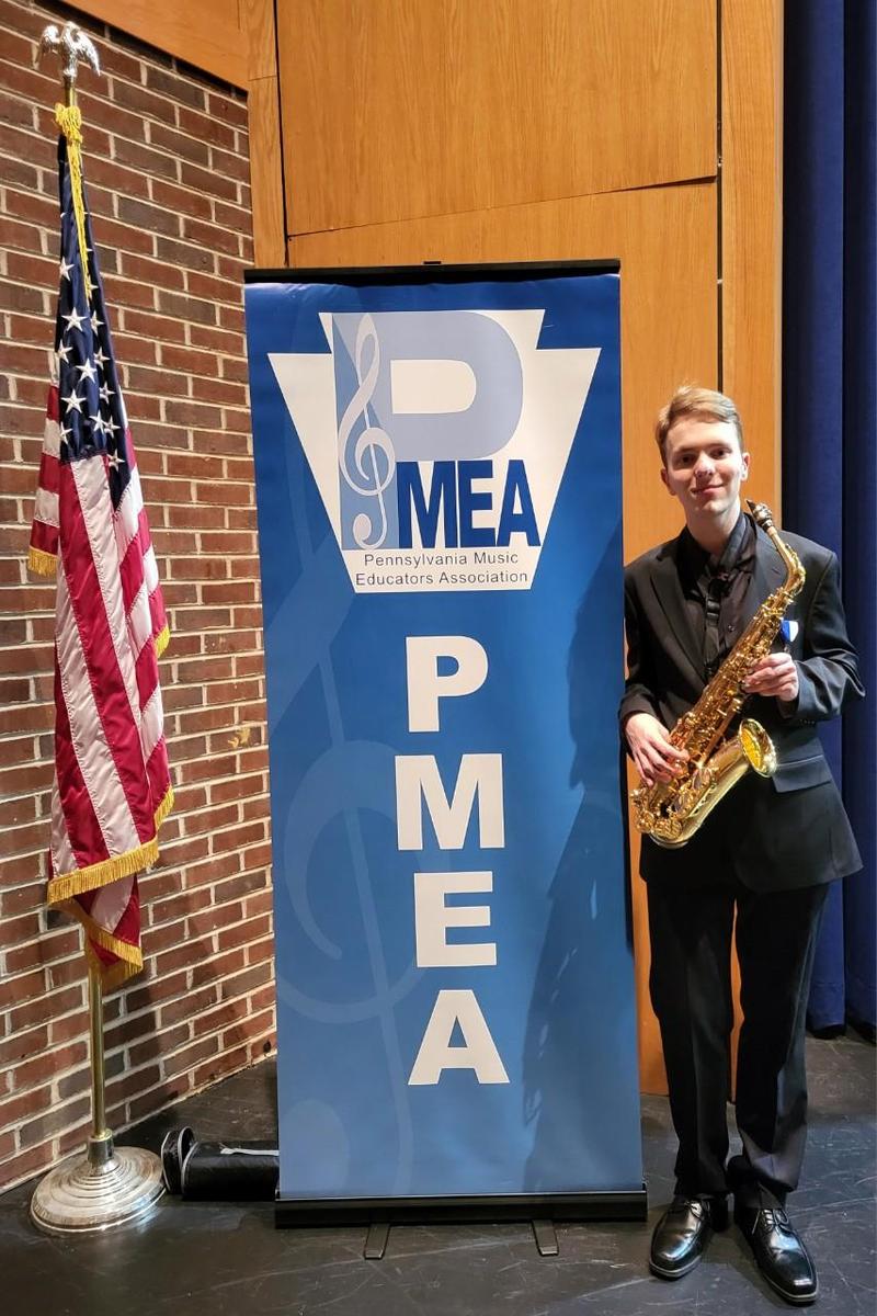 Image of US Flag and musician holding his saxophone with text that says PMEA Pennsylvania Music Educators Association
