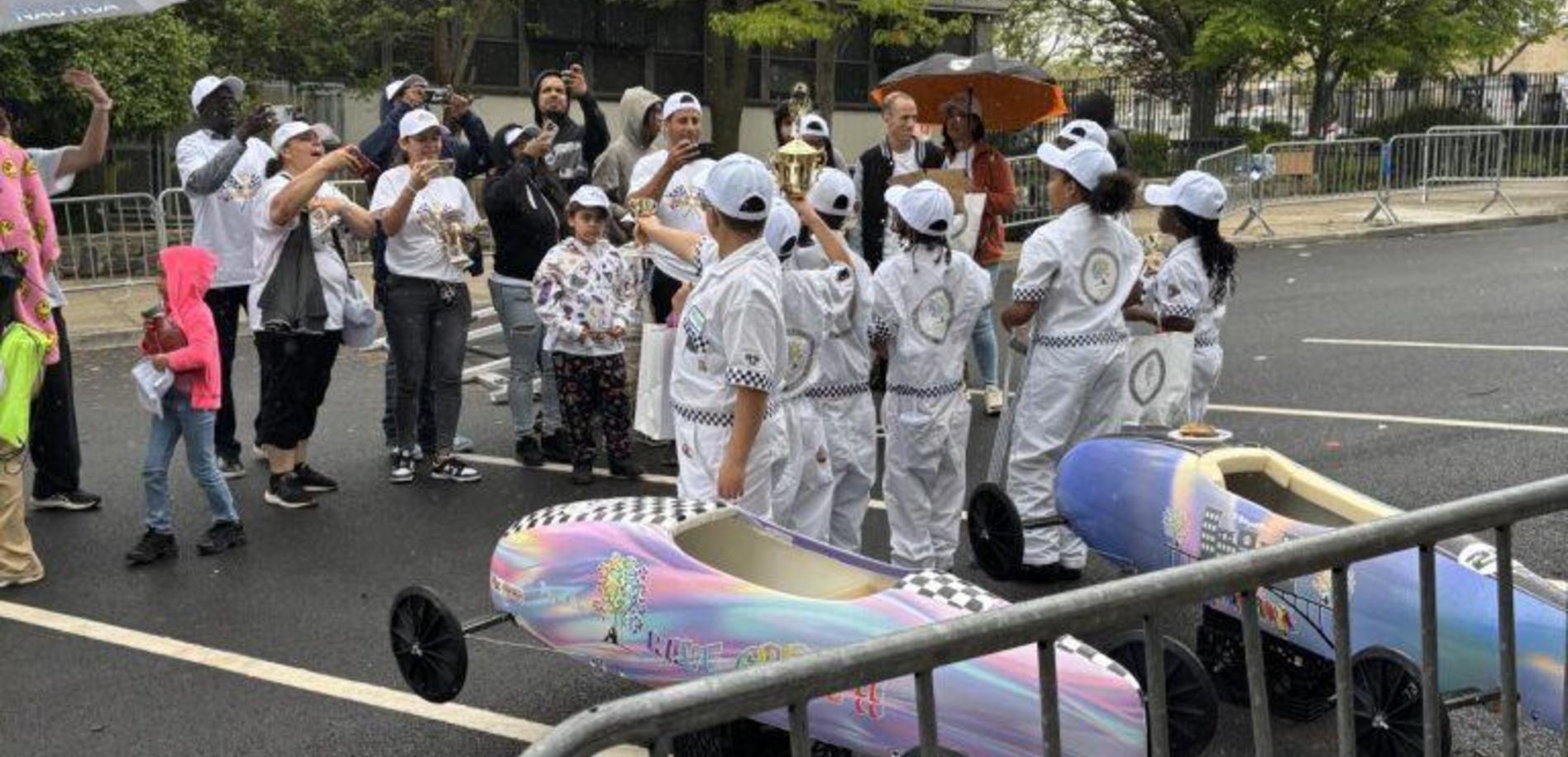 A group of people in white outfits celebrating a race with decorated carts and trophies.
