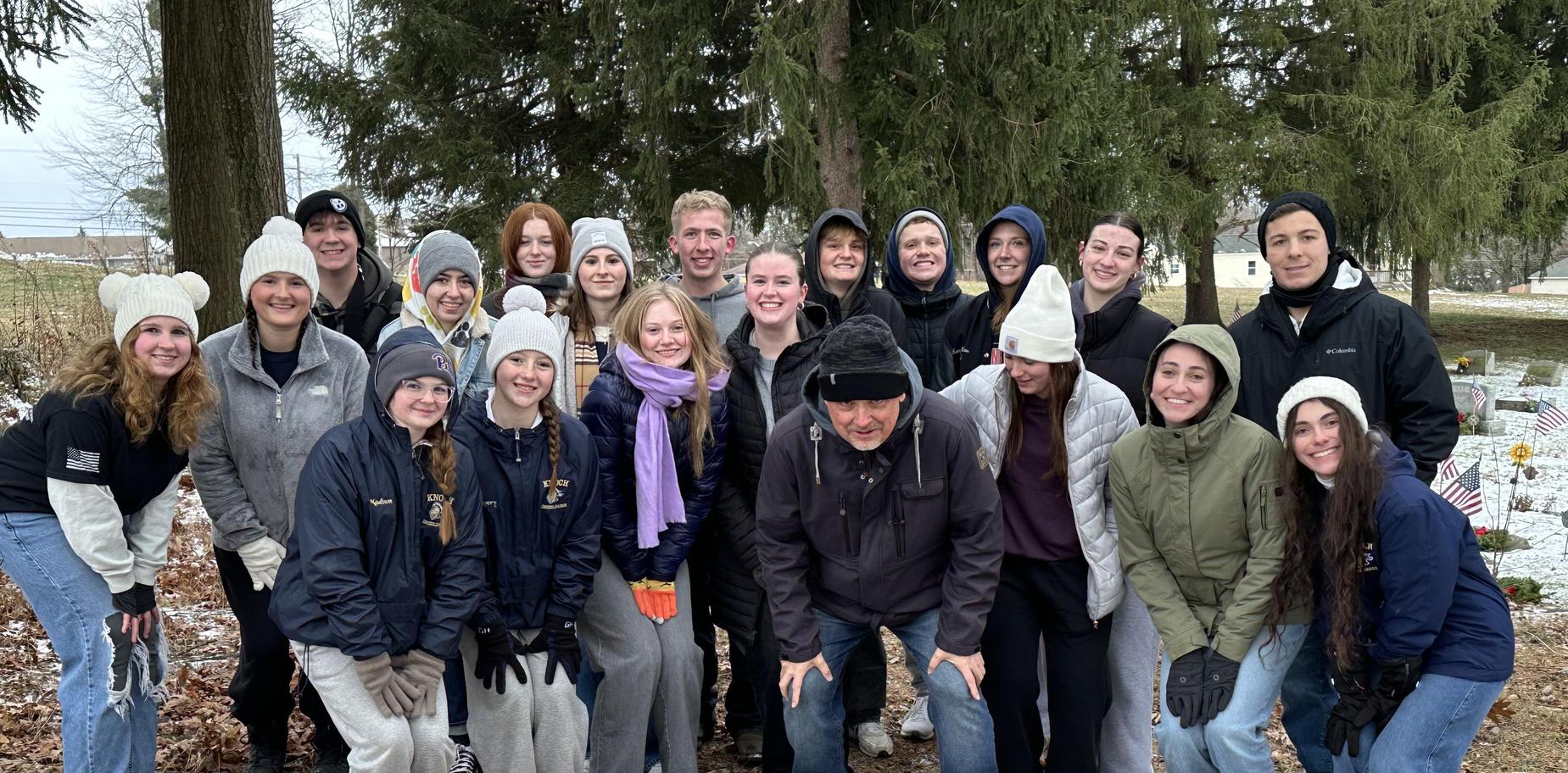 Group photo of students in winter clothing at a cemetery.