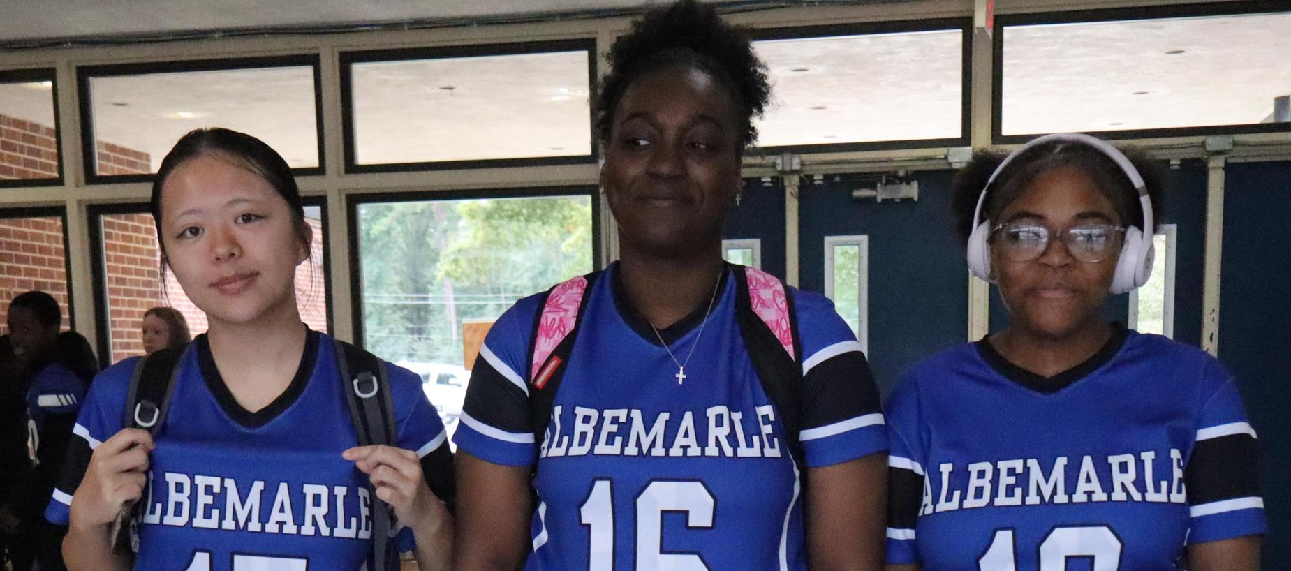 Three individuals wearing blue team jerseys numbered 15, 16, and 13.