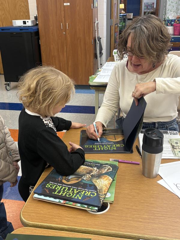 Author signing book while girl looks at book