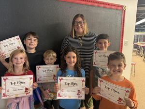 Students smiling with certificates alongside the principal.