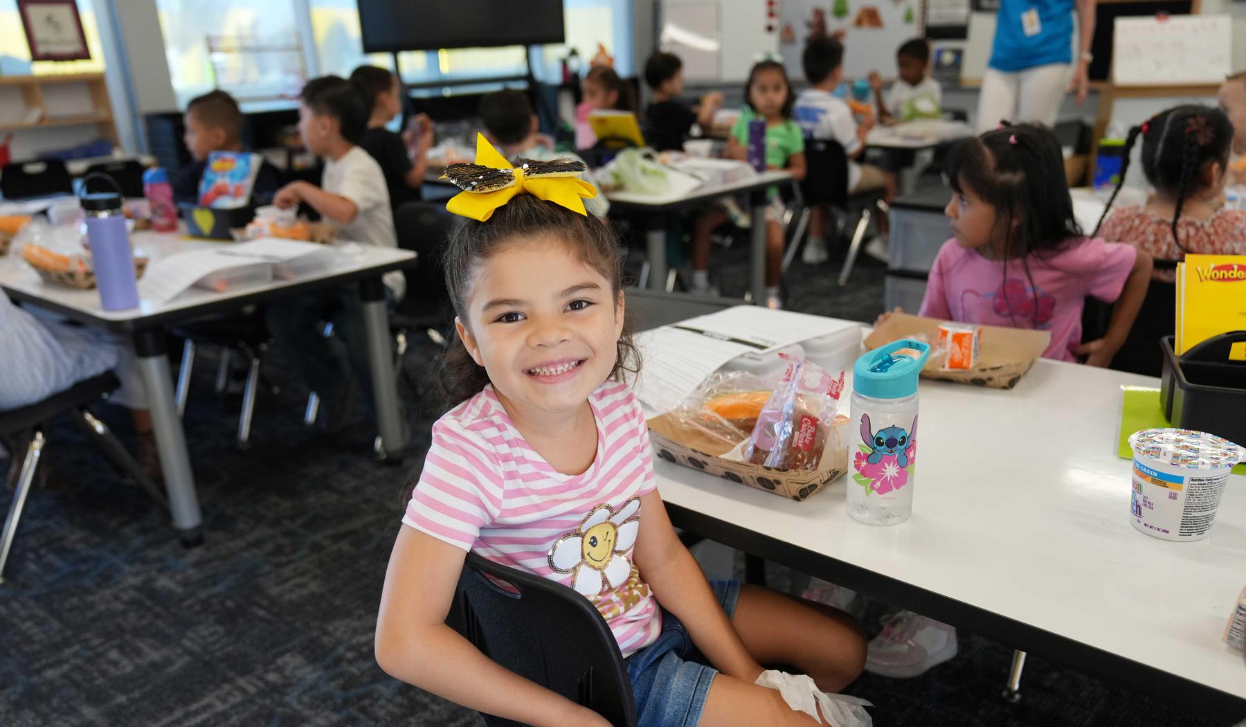 girl sitting in classroom with breakfast tray