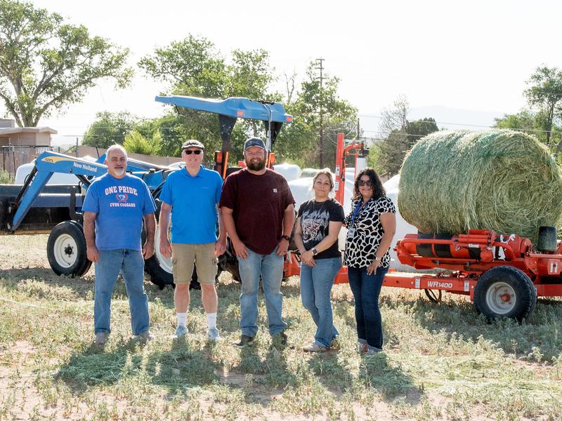 Five CVHS staff members posing for a photo in front of the tractor and hay bale
