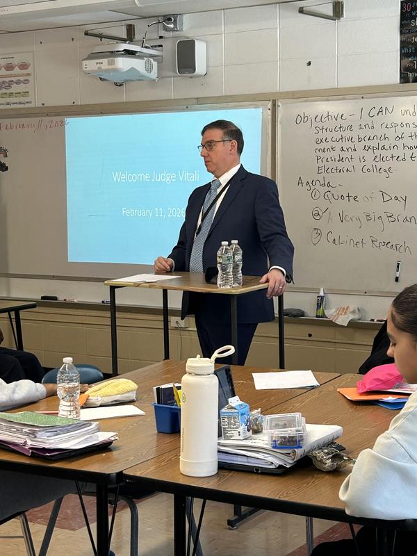 Judge Vitale standing at a podium speaking in a classroom.