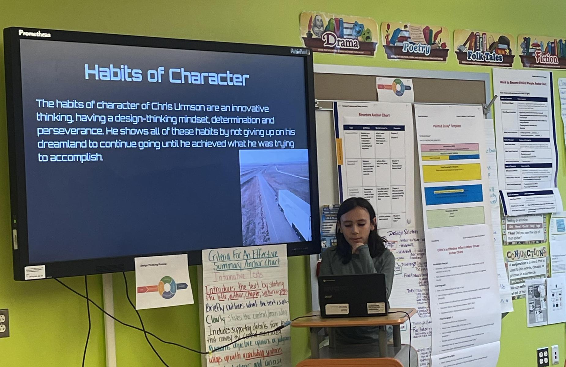 Student presents on habits of character using a laptop and a screen.