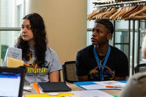 Two students listen intently to a peer