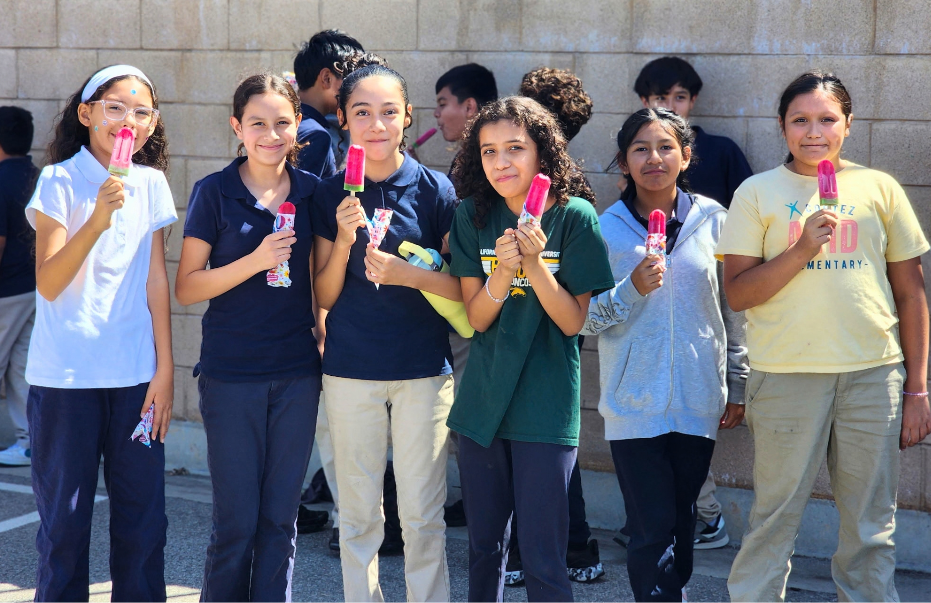 Cortez students with popsicles on PBIS Kickoff day. Homepage shuffle banner. Students are in uniform with blue pants and light blue shirts.