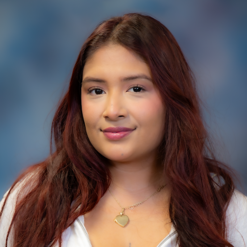 Young woman with long, wavy red hair, wearing a white hoodie, smiling softly. Join us in celebrating Josary Wicab as our Volunteer of the Year 2025-26.