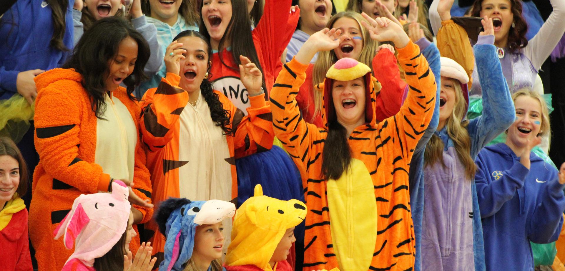 Enthusiastic group of girls in animal onesies, celebrating at an event.