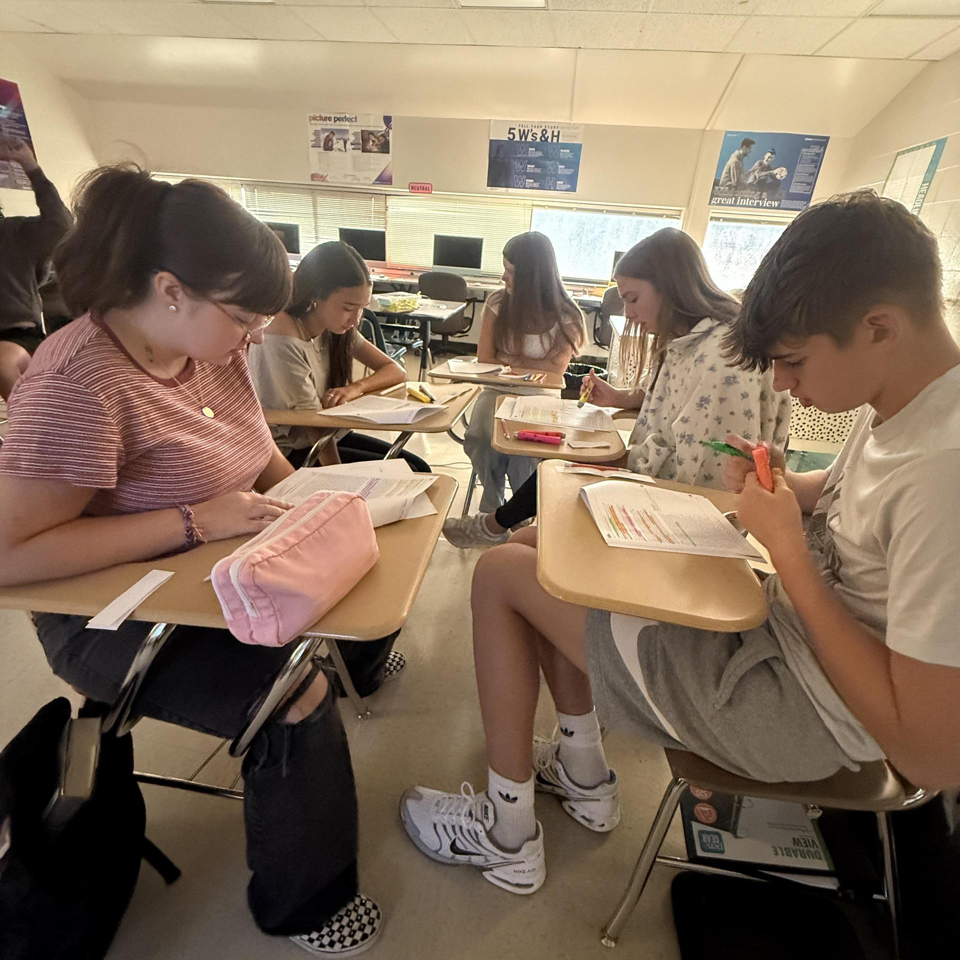 Students studying quietly at individual desks, working on assignments together.