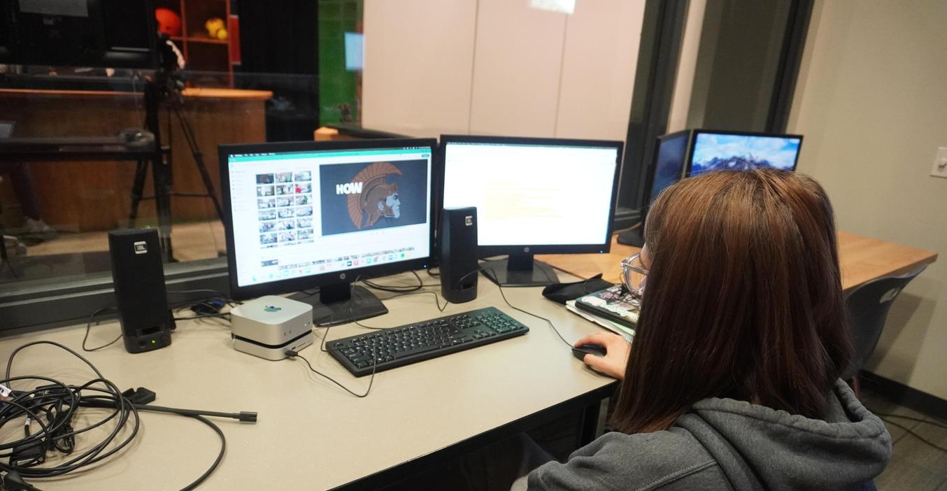 A person sitting at a desk using a computer with various screens and devices.