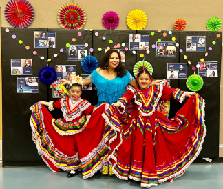 two girls in folkloria outfits in front of school lockers with teacher