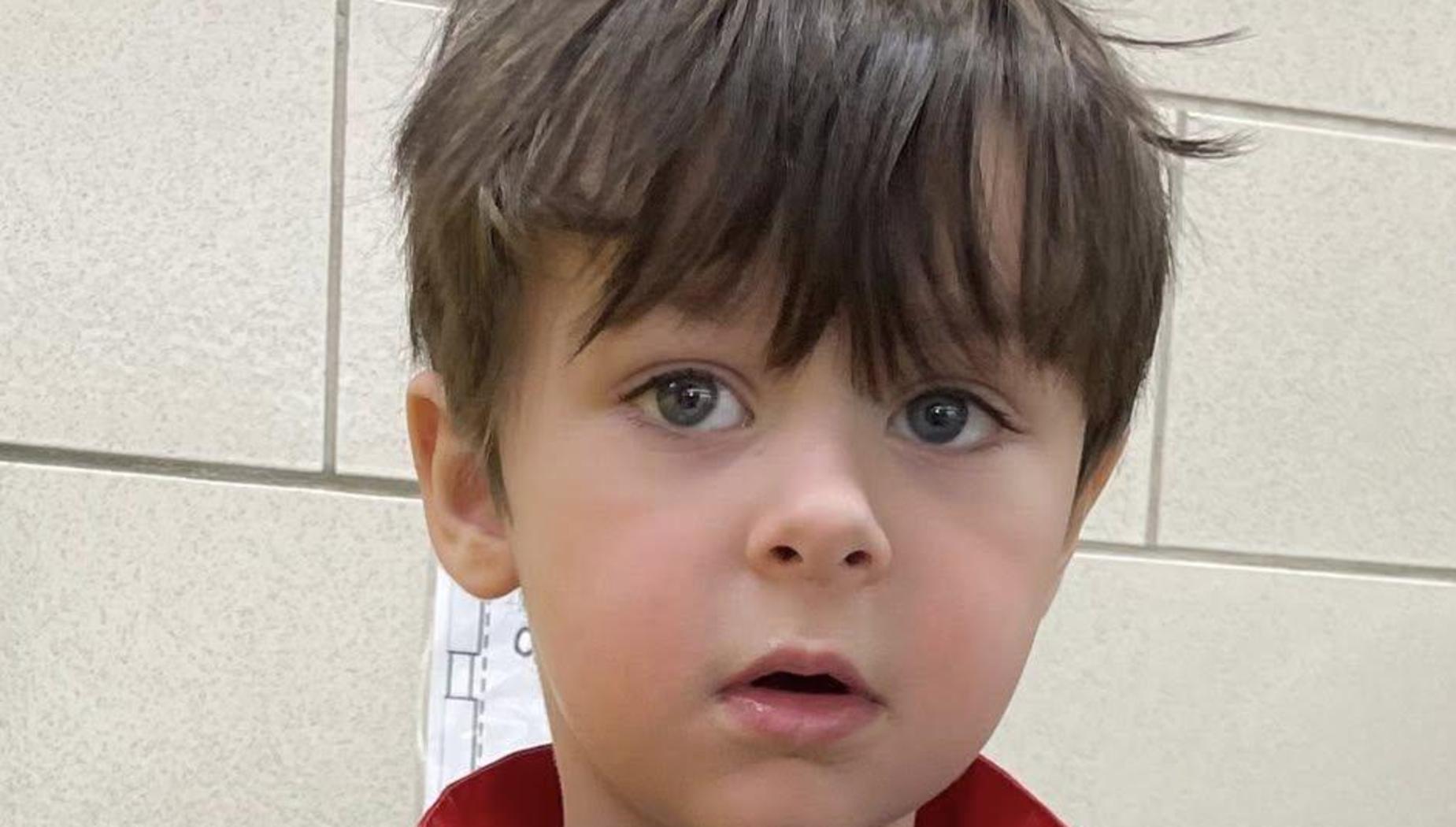 Child in a royal costume with gold details and a badge.