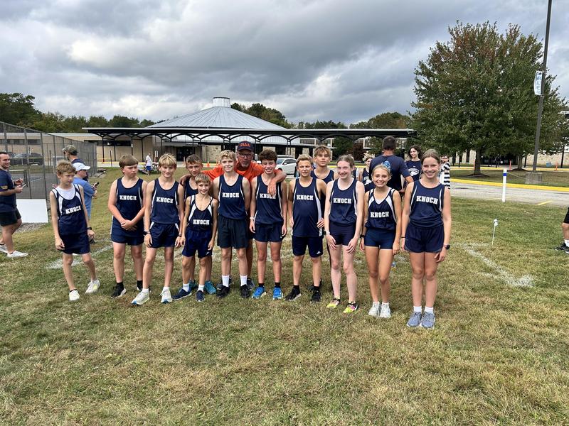 group of youth runners in uniforms posing on grass