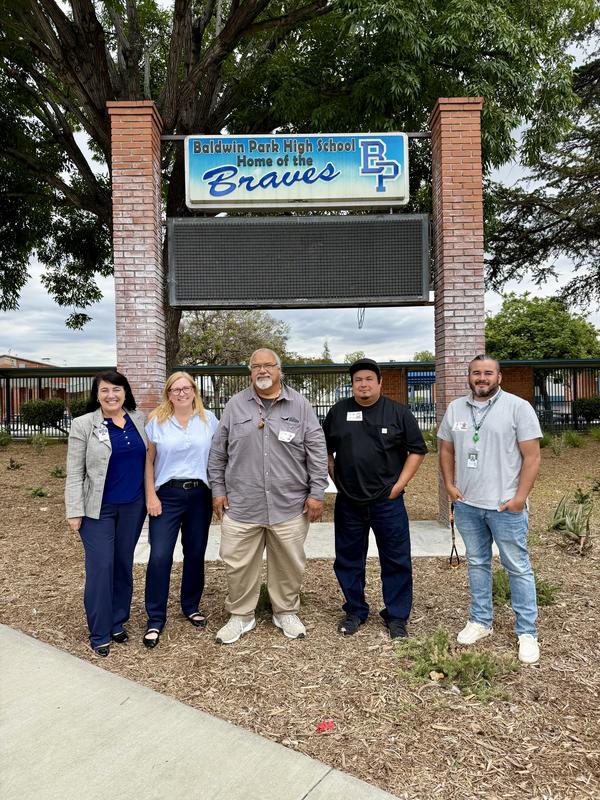 Dr. Angela Salazar, Baldwin Park Unified School District Assistant Superintendent of Student Achievement, Deborah Madrigal, Principal of Baldwin Park High School, Eric Ortega, Chris Nejo, and John A. Machado, representatives from the Pala Band of Mission Indians pose for a group photo together in front of Baldwin Park High School.
