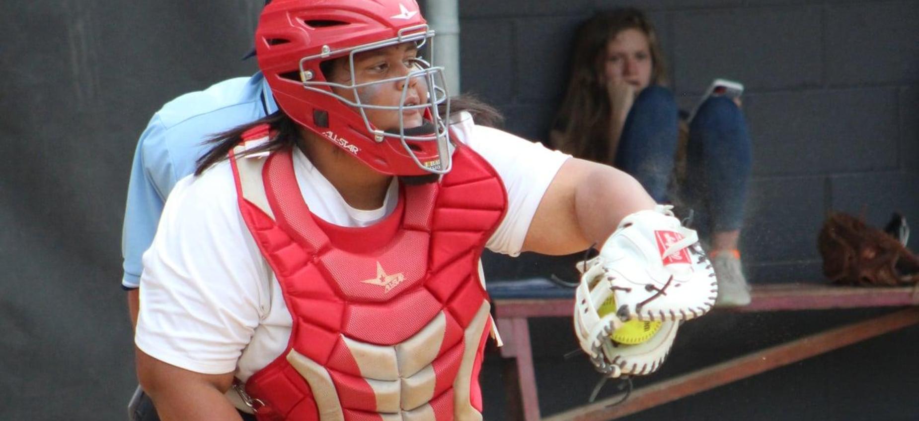 A softball player catches the ball.
