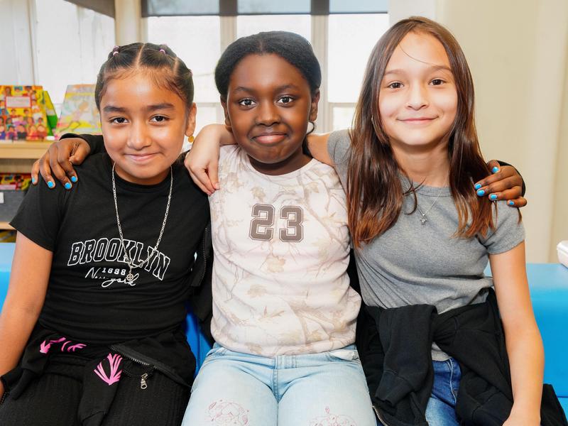 Three elementary-aged girls smiling together for a photo.