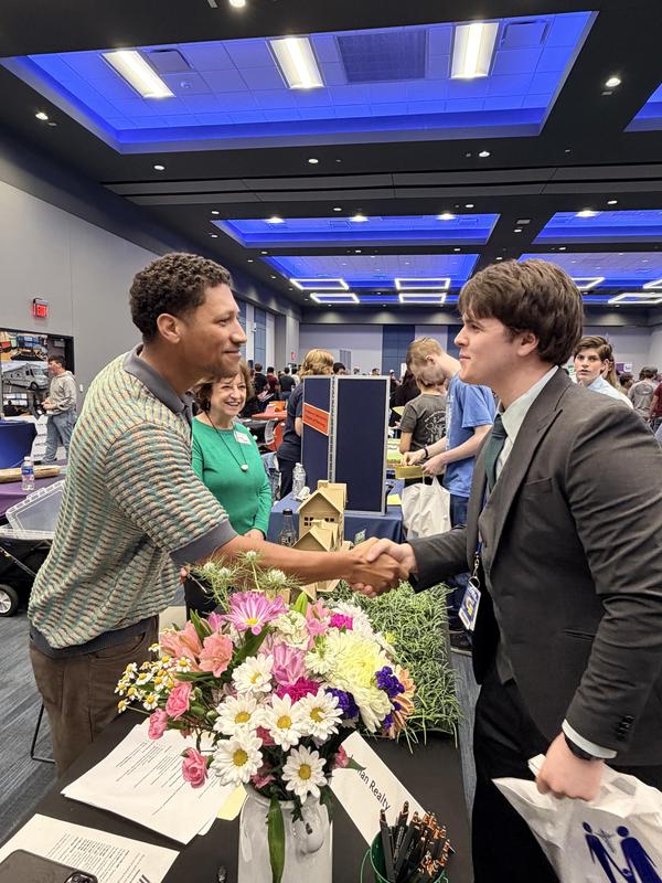 Student shaking someone's hand at a career fair event