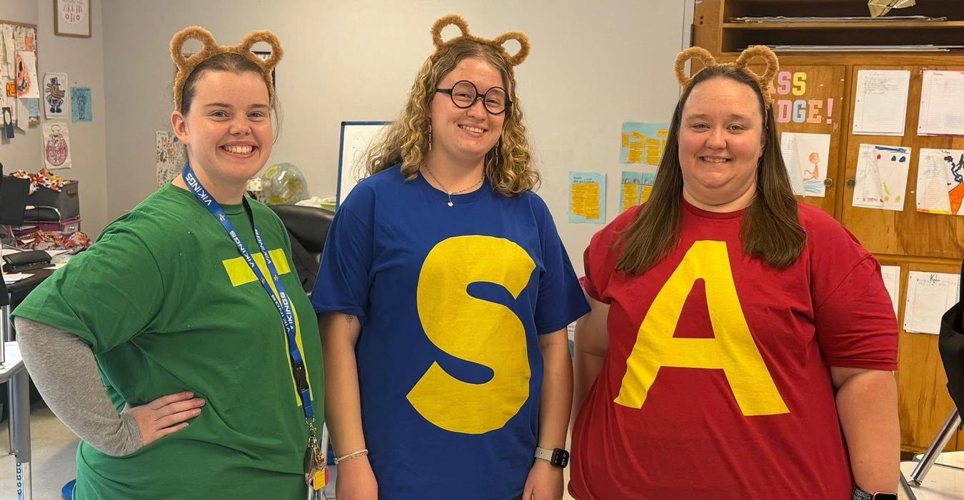 Three women wearing colorful shirts with large letters.