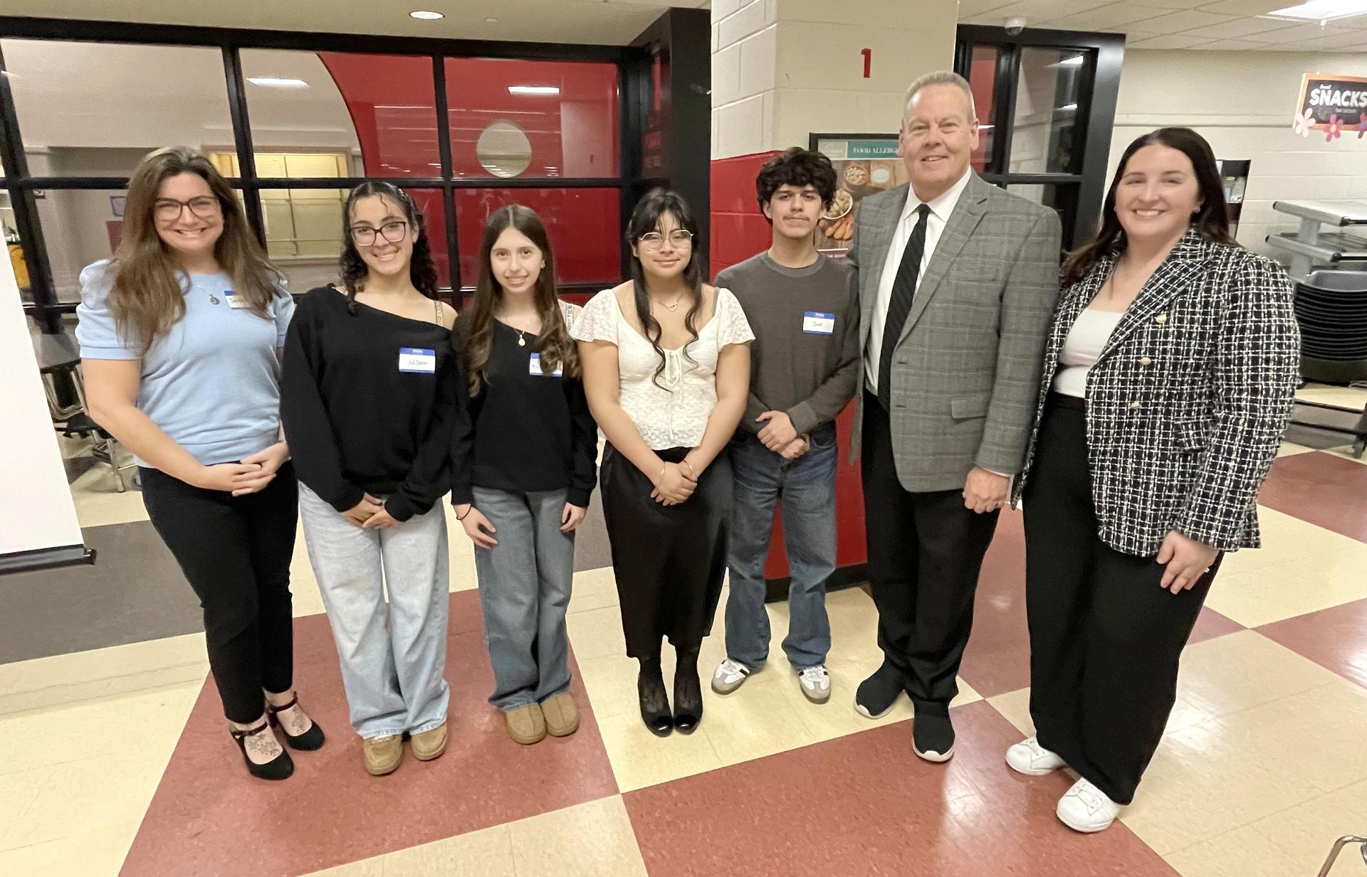 Group of students and adults posing in a school hallway.