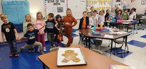 kindergarten class surrounds a table with a giant gingerbread man