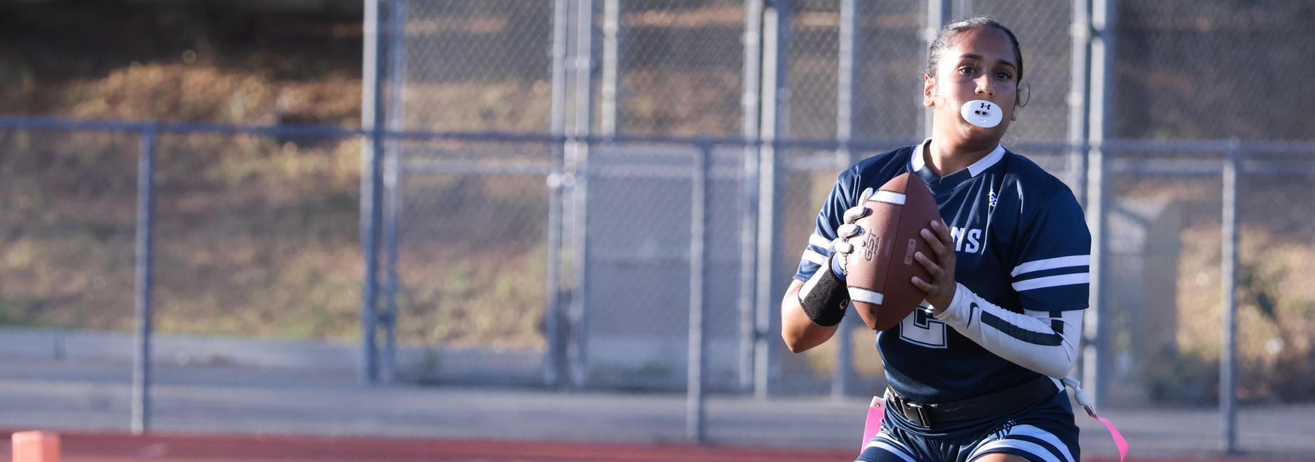 A young female athlete throwing a football on a sports field.
