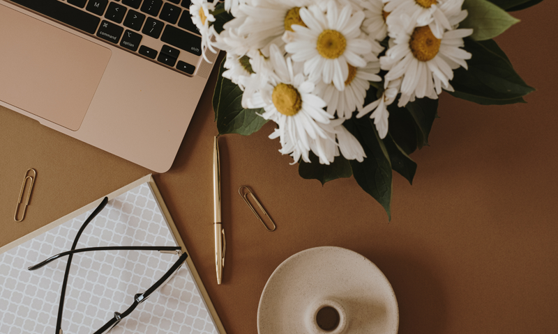 desktop with laptop, pen and flowers