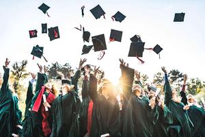 Graduates in caps and gowns joyfully tossing their hats into the air.