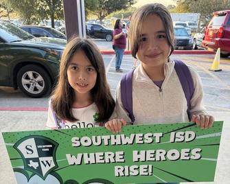 Two girls holding green SW sign