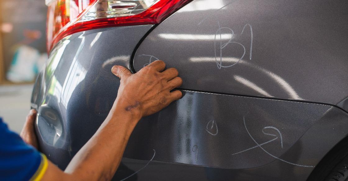 Man looking at a dent in a car