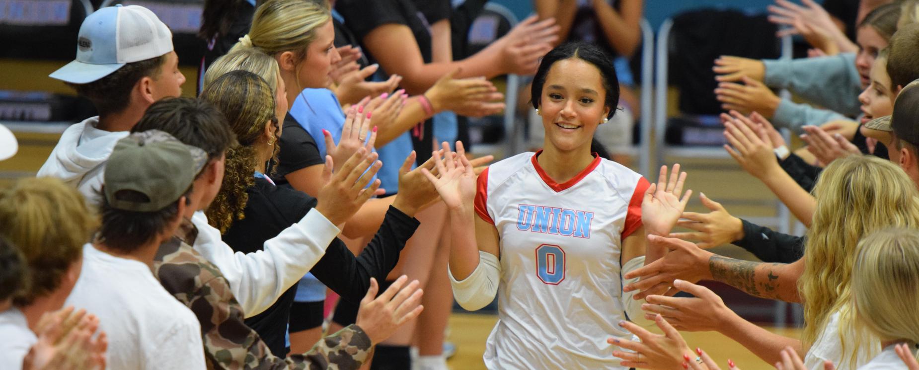 Volleyball player running onto court, giving high-fives to fans