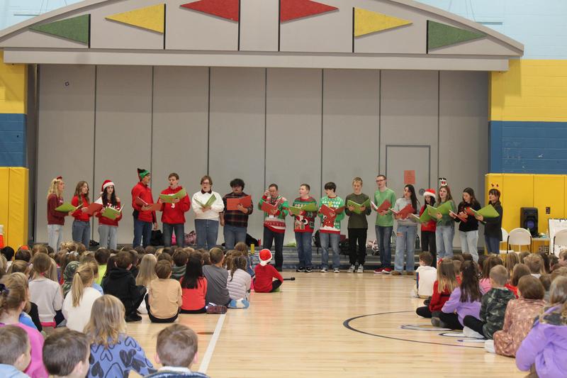 group of singers stand in front of seated children