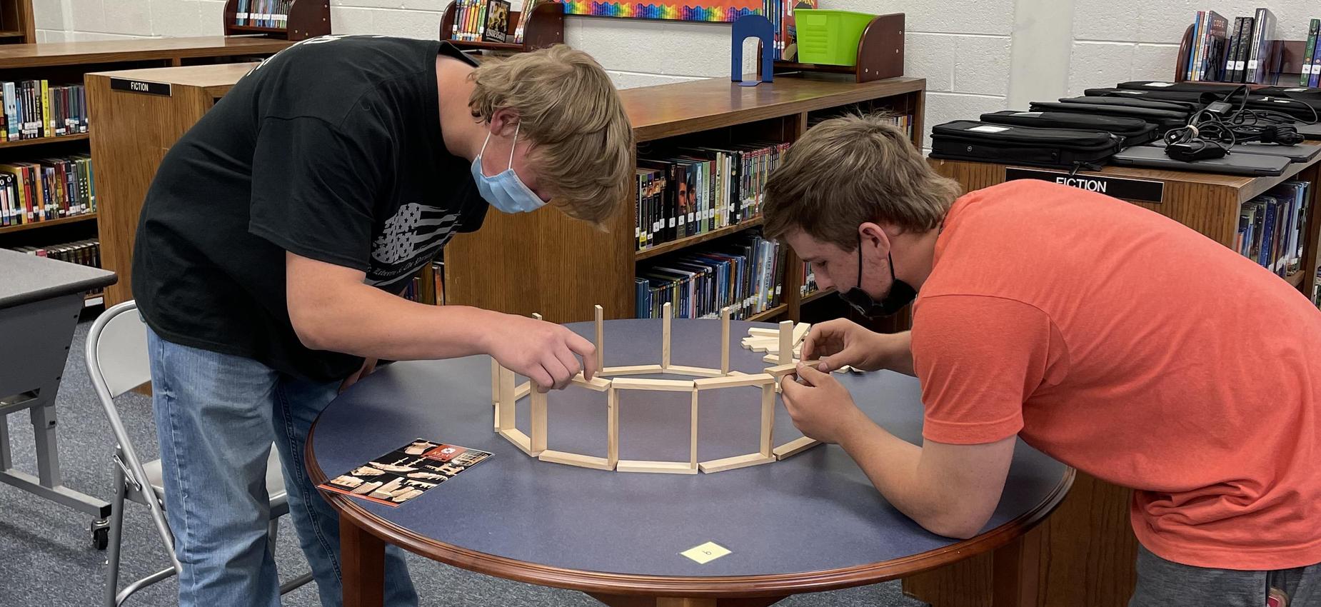 Two students work with blocks in a library.