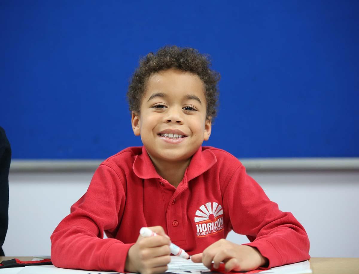 Elementary student smiling in a classroom.