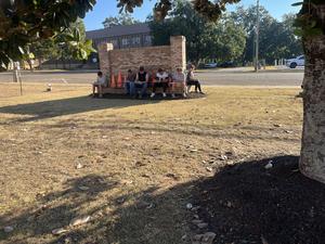 boys sitting behind the PHS sign in the front yard, writing