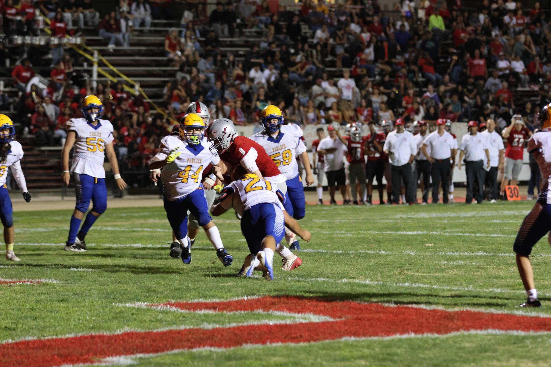 Varsity football players in action against Parlier 65