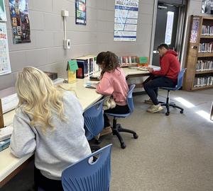 Three students reading at the counter.