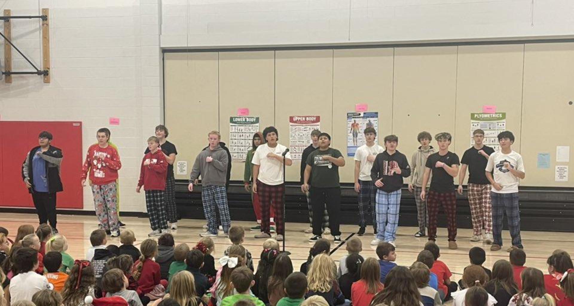 Teen boys performing in front of an audience of younger students during an event in the gym.