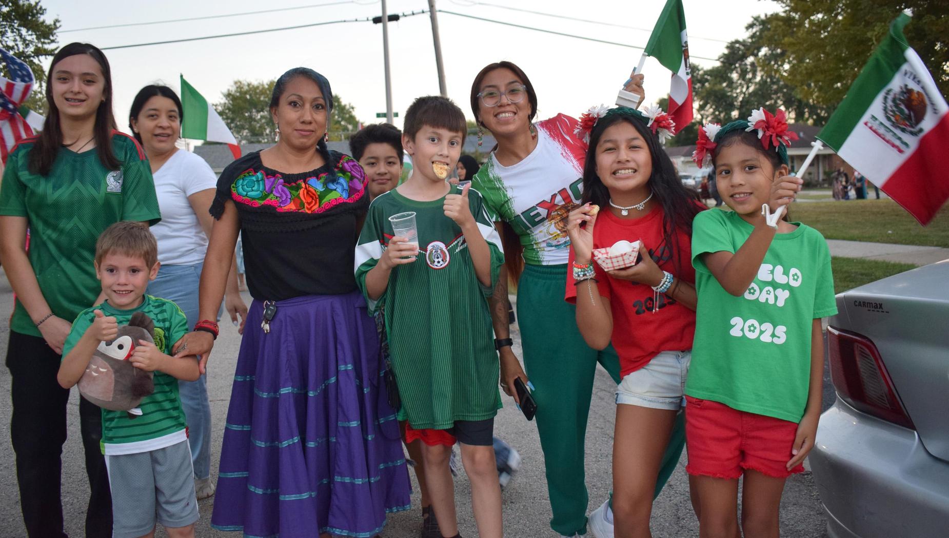 Community members celebrating cultural heritage with flags and traditional attire outdoors.