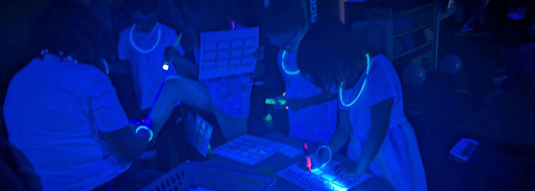 Children engaging in a glow-in-the-dark activity with neon accessories.
