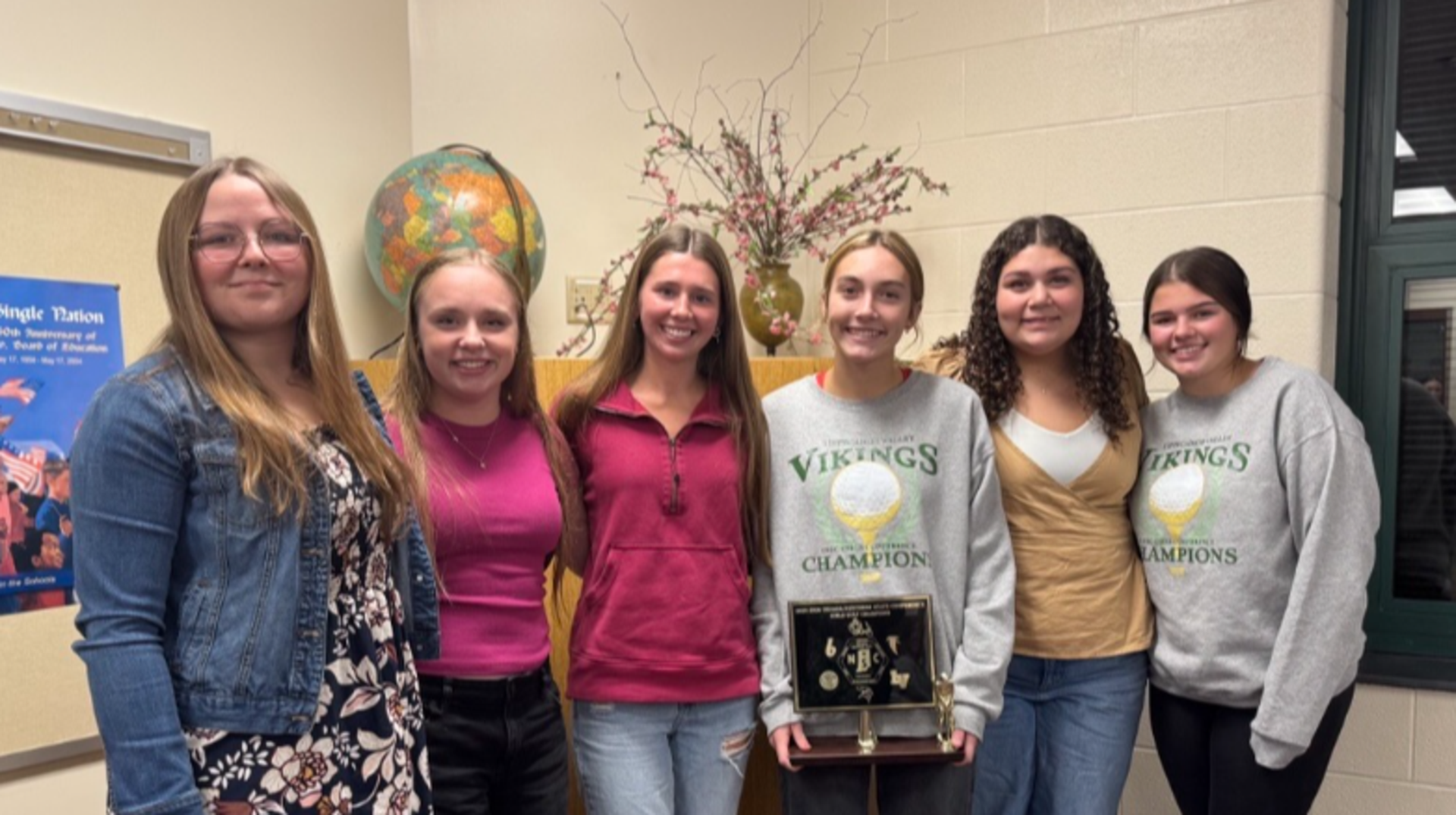 Group of six individuals posing together, holding a trophy.