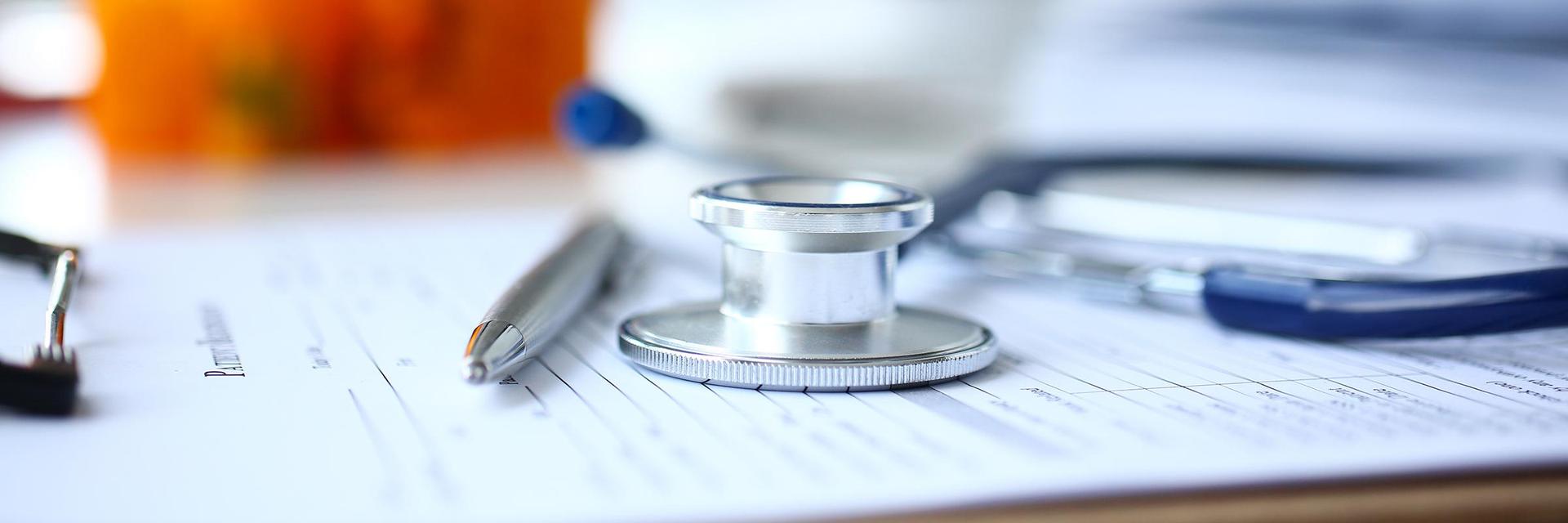 A stethoscope and a pen on top of paperwork