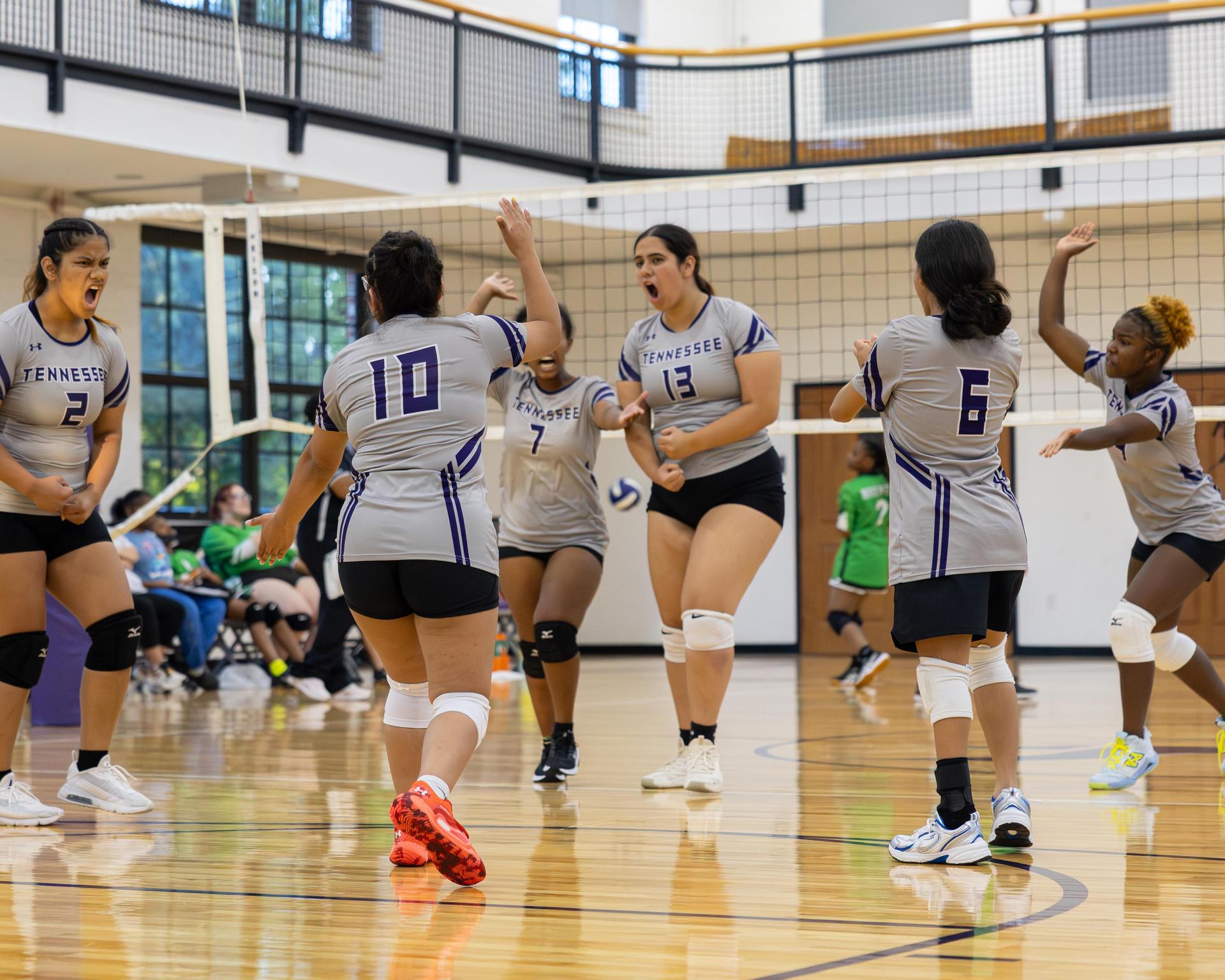 Players celebrating in a huddle during a volleyball game.