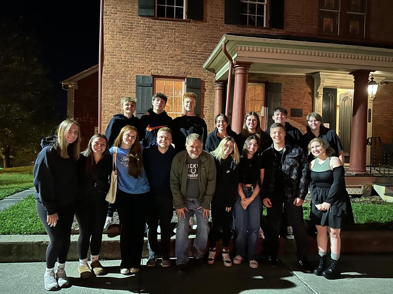 group of high school students posed in front of an old house