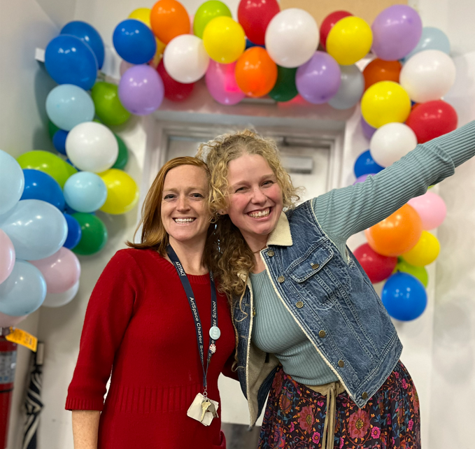Smiling Staff members with balloon arch backdrop