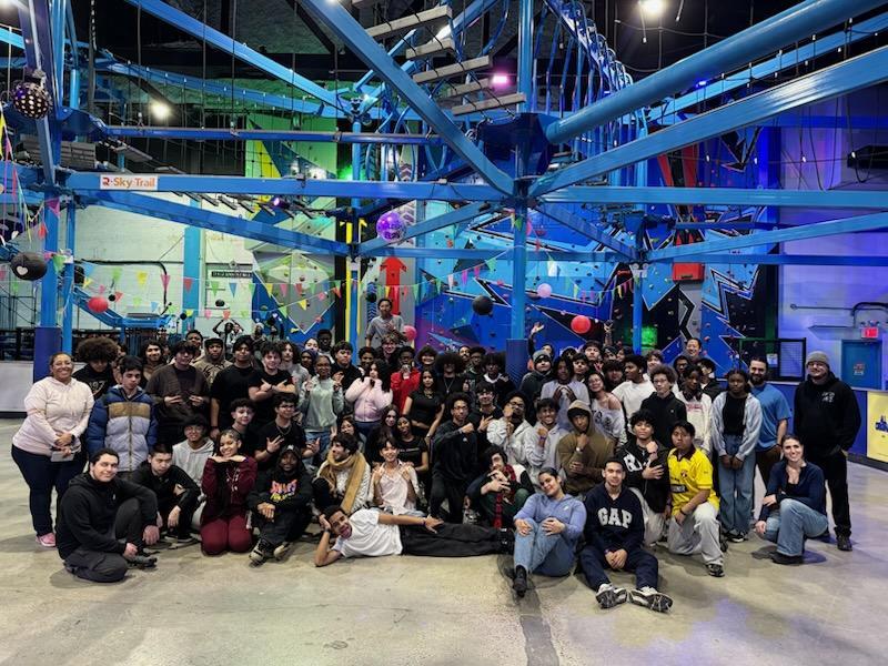 A large group poses together in a colorful indoor entertainment venue.