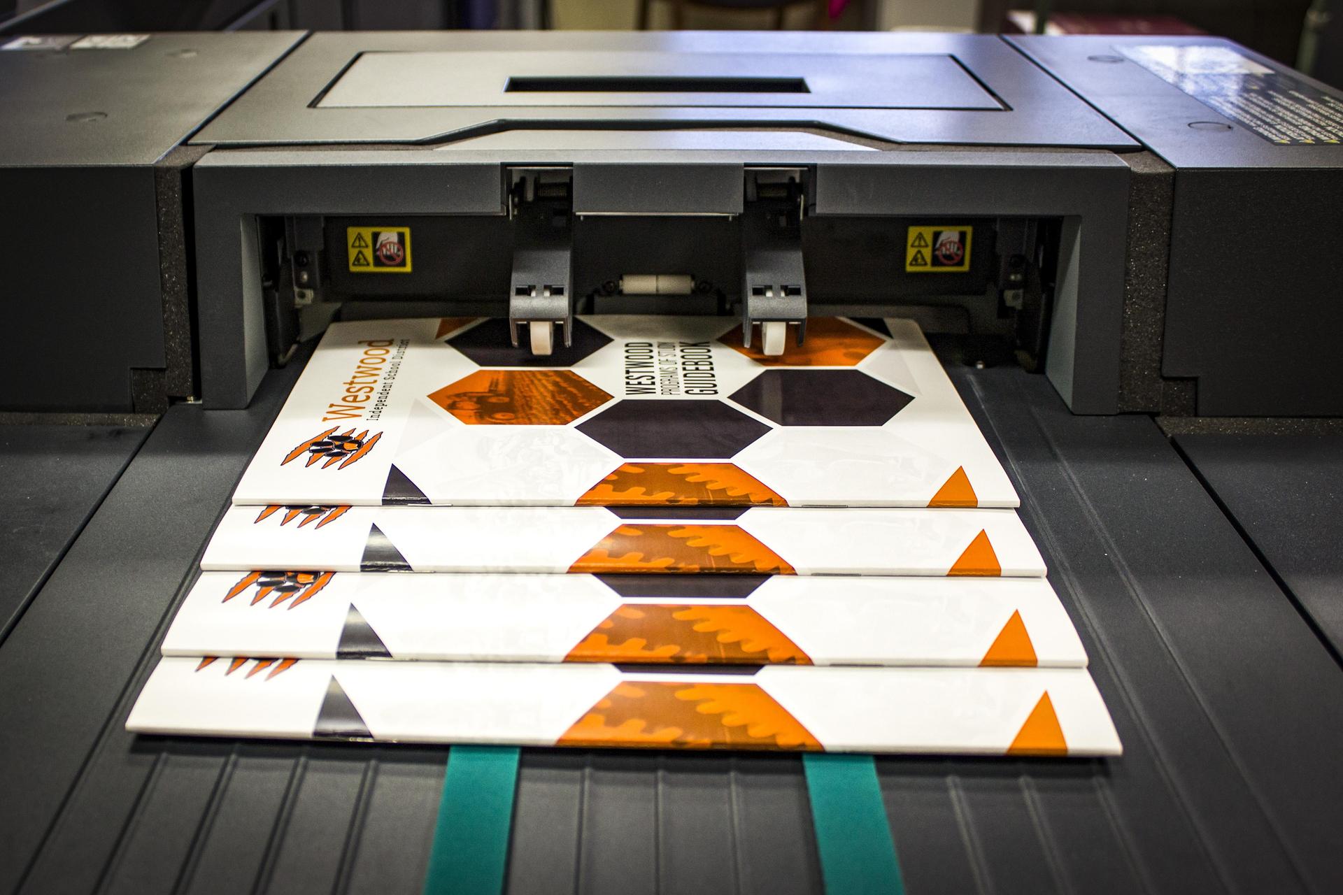 Stack of professionally printed brochures and booklets produced by the Region 7 Print Center.